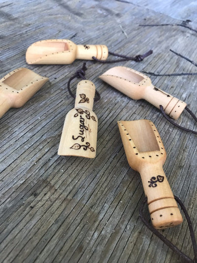 Small Wooden Sugar Scoops.  Measure up to one teaspoon.  Has wood burned designs with the word "sugar" and leaves and dots.  