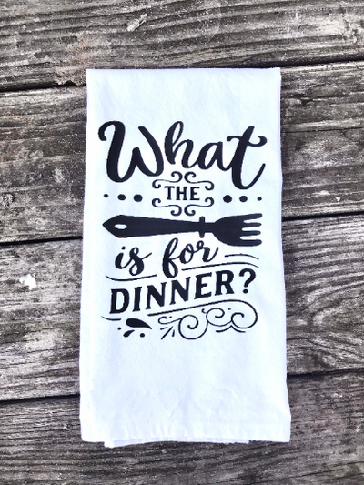 A white, cotton kitchen towel with a design that says "what the fork is for dinner" in black vinyl.  A cute kitchen gift.