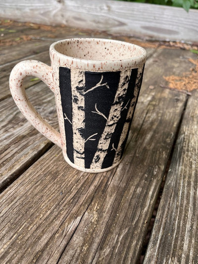 Handmade Pottery Mug with carved out birch trees and tan speckled glaze.