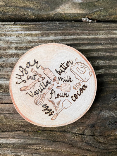 Wood Slice Fridge Magnet that has a wood burned design of different baking appliances and baking ingredients that are positioned in the shape of a heart.  A great kitchen gift for those who bake!