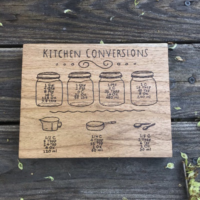 Useful Kitchen Signs.  This 10 inch by 2 inch sign has four mason jars that each have their own common measuring conversions.  Below the mason jars is a 2 measuring cups and measuring spoons that have more smaller conversions.  All wood burned by hand.  Can stand up on it's own or has a sawtooth bracket so you can hang on the wall.