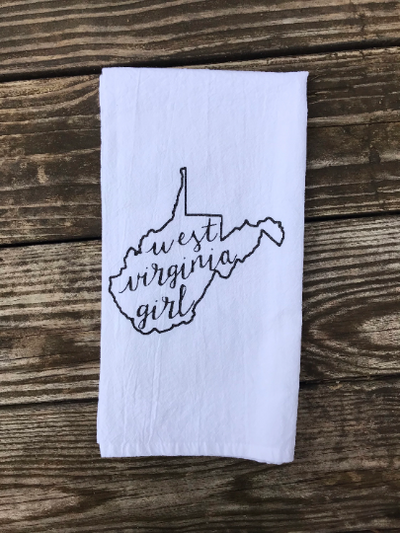 A white, cotton kitchen towel with black glitter vinyl of the state of WV with the words "west virginia girl" inside the state.  A great kitchen gift!