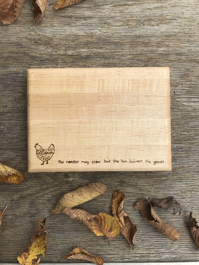 Handmade Maple Wood Cutting Board.  Has a wood burned design on the bottom with a chicken and quote "the rooster may crow but the hen delivers the goods".  Can have a personalization on the top.