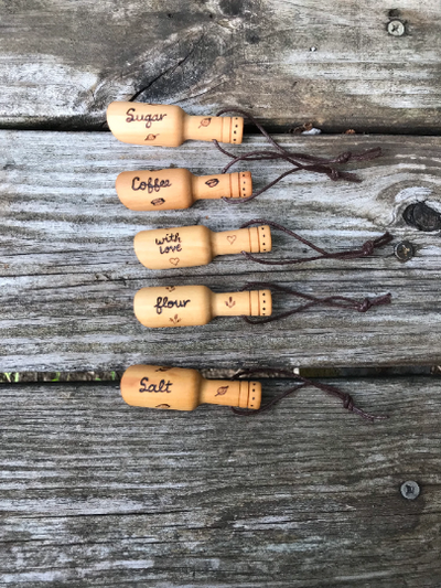 Set of 5 small wooden scoops with wood burned designs.  One coffee scoop, one sugar scoop, one flour scoop, one salt scoop, and one that says with love with hearts.  Also measure up to 1 teaspoon.  Cute kitchen gifts!